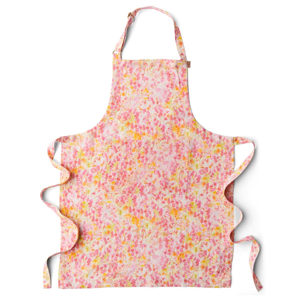 A pink and yellow floral-patterned linen apron with adjustable straps and a ruffled front.