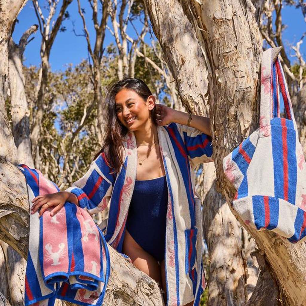 Woman in a tree with the Lobster Fan Club bag and robe