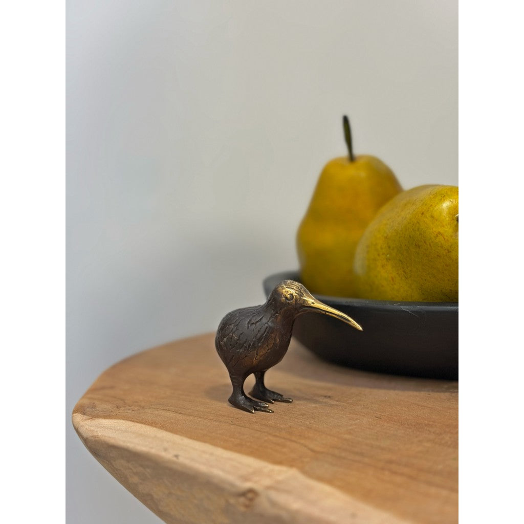 Brass kiwi beside a bowl of pears