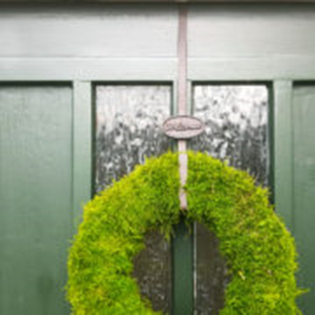 Wreath hung on a front door with the Welcome wreath hanger
