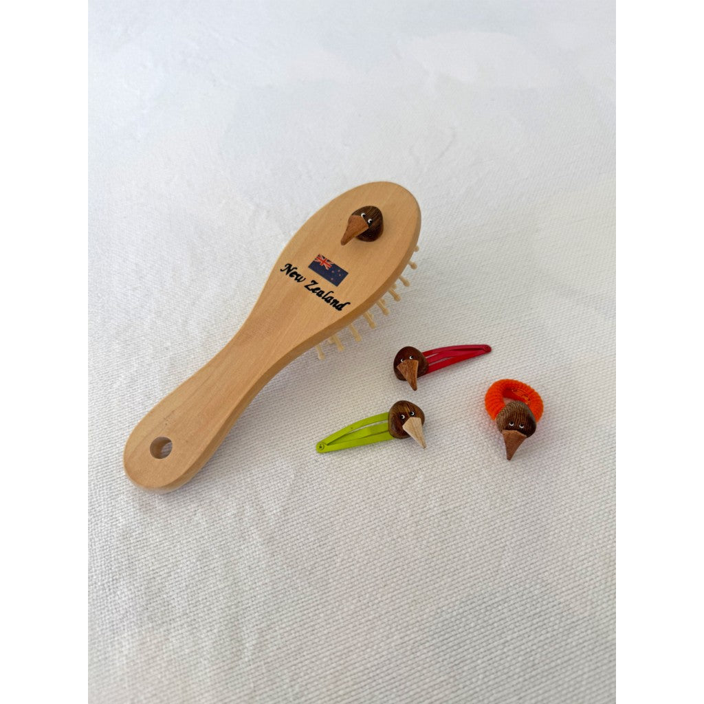 Kiwi hair clips beside a wooden hairbrush