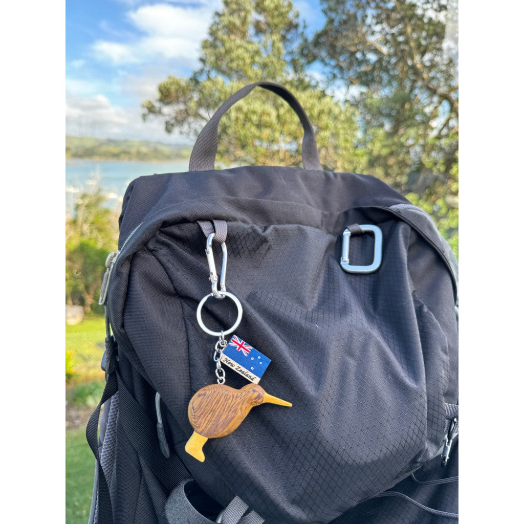 Wooden kiwi keyring on a backpack by the water