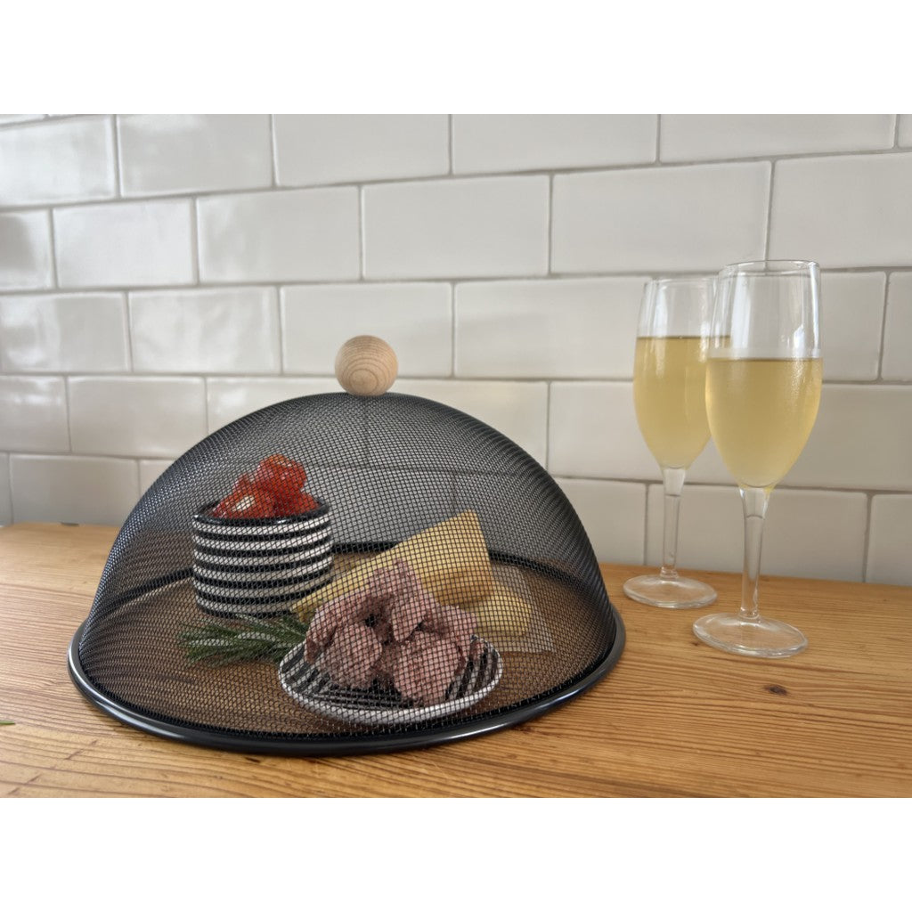 Black mesh food cover over a platter on a kitchen bench
