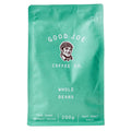 A display of Good Joe Coffee Co.'s West Coast Roast Whole Beans is showcased in a rustic setting. The packaging features a clean, modern design with earthy tones, emphasizing the premium quality of the coffee. The bags are neatly arranged, highlighting the brand's logo and product name, creating an inviting and appealing presentation for coffee enthusiasts.