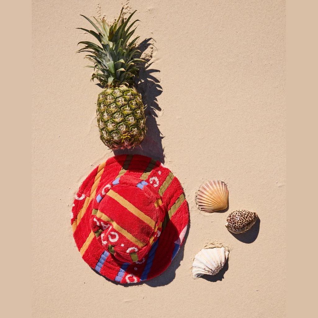Ciao Stripe hat on the sand with a pineapple and shells