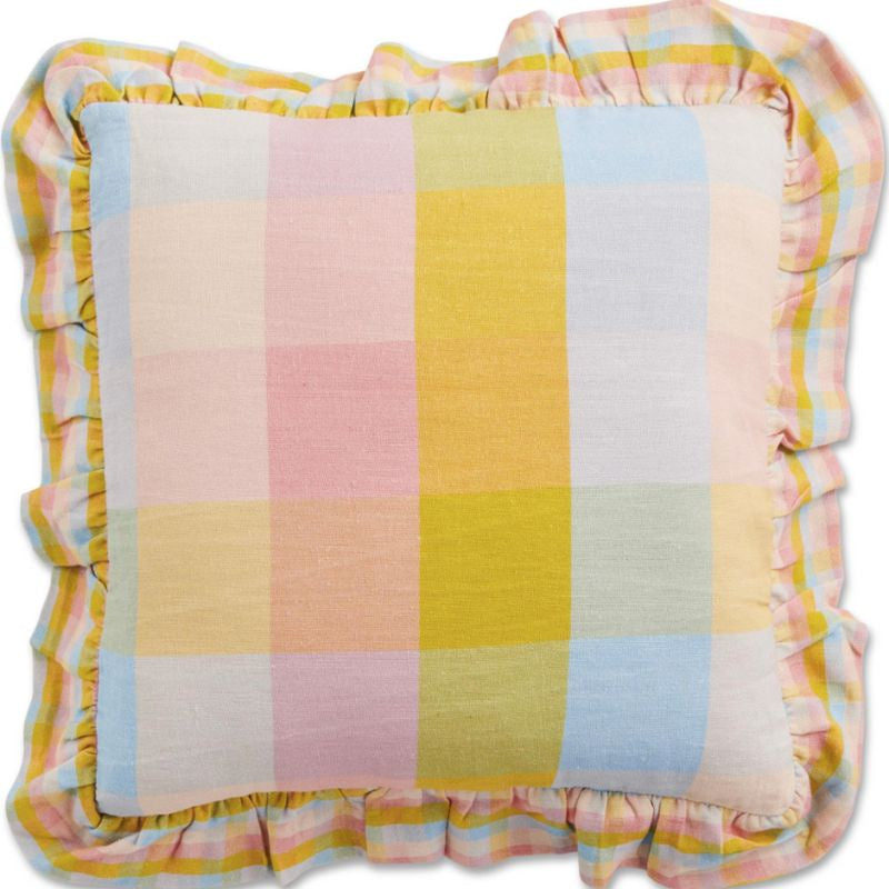 The image likely features a vibrant and colorful Corfu Tartan Cushion from Kip &amp; Co, available at Cove. The cushion is designed to brighten up any space with its lively tartan pattern. It is also eco-friendly, aligning with sustainable living practices.