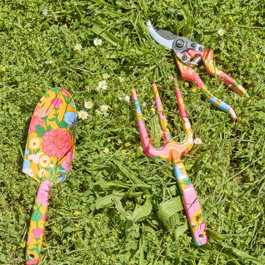 The image shows a set of yellow garden tools and gloves. The tools include a trowel, a hand fork, and a pair of pruning shears, all featuring bright yellow handles. The gloves are also yellow, matching the tools, and appear to be made of a durable material suitable for gardening tasks. The set is neatly arranged, likely on a plain background, emphasizing the vibrant color and cohesive design of the gardening set.