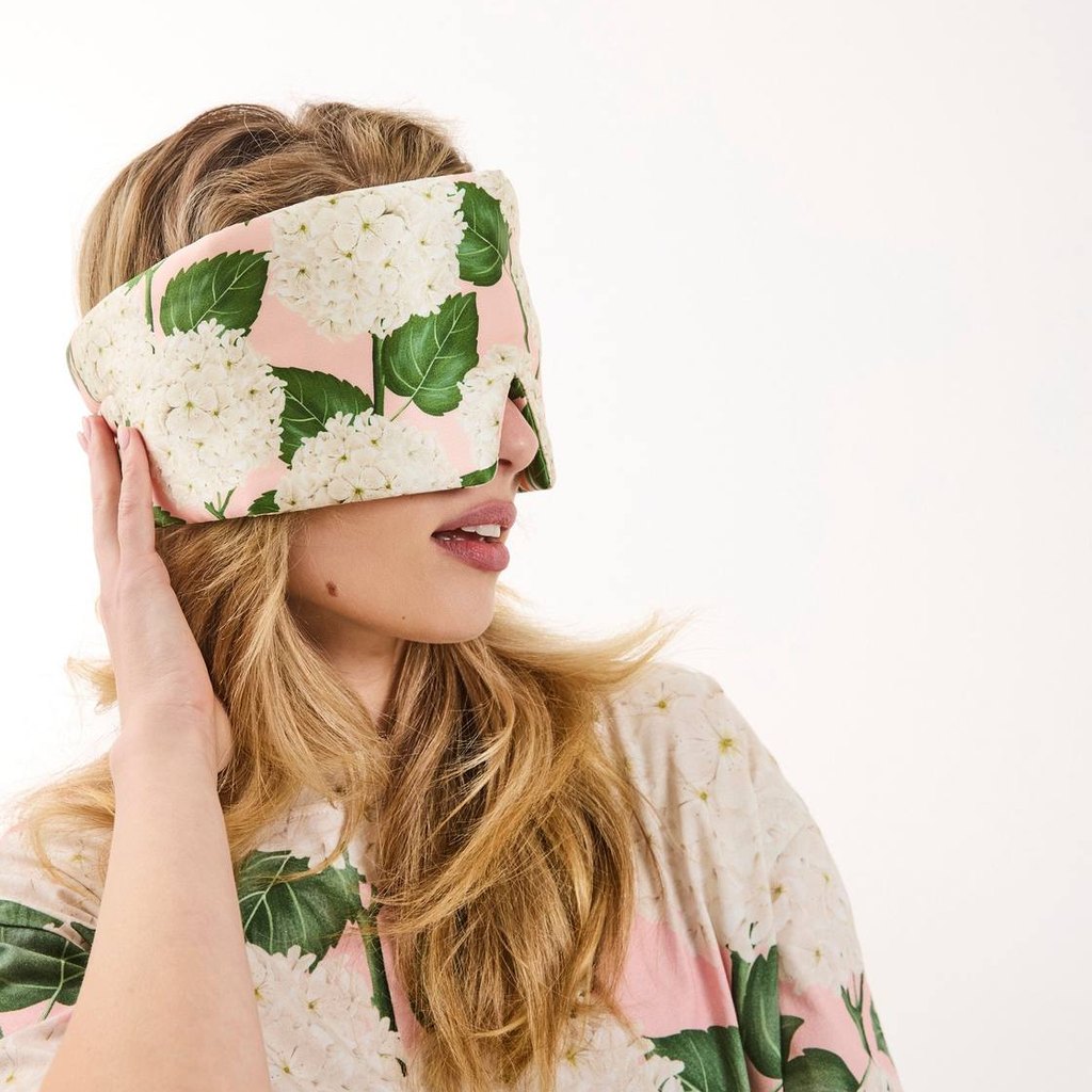 Woman in floral pyjamas wearing the Hydrangea Pink eye mask
