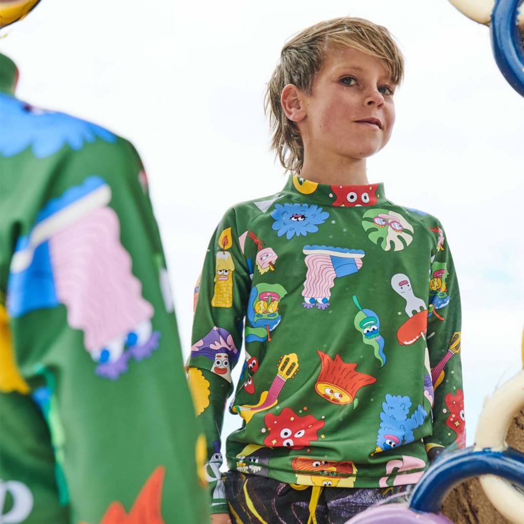 Discover the Kip & Co Nature Things Rash Vest at Cove! This eco-friendly rash vest offers UPF 50+ protection and features camping designs on a forest green background, making it an ideal choice for sun protection.