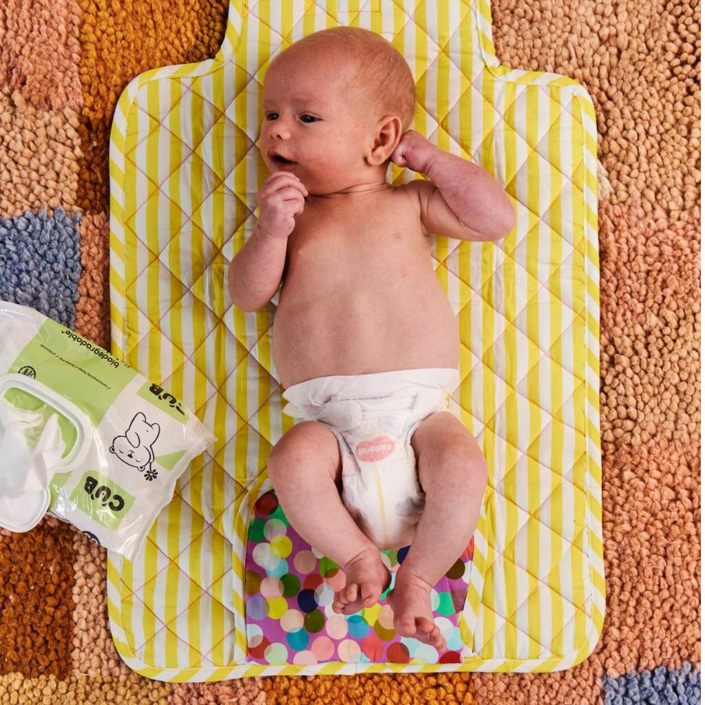The image likely showcases the Kip & Co Confetti Pink Baby Change Mat available at Cove. The mat features a playful confetti design in pink tones, emphasizing its eco-friendly and stylish appeal.