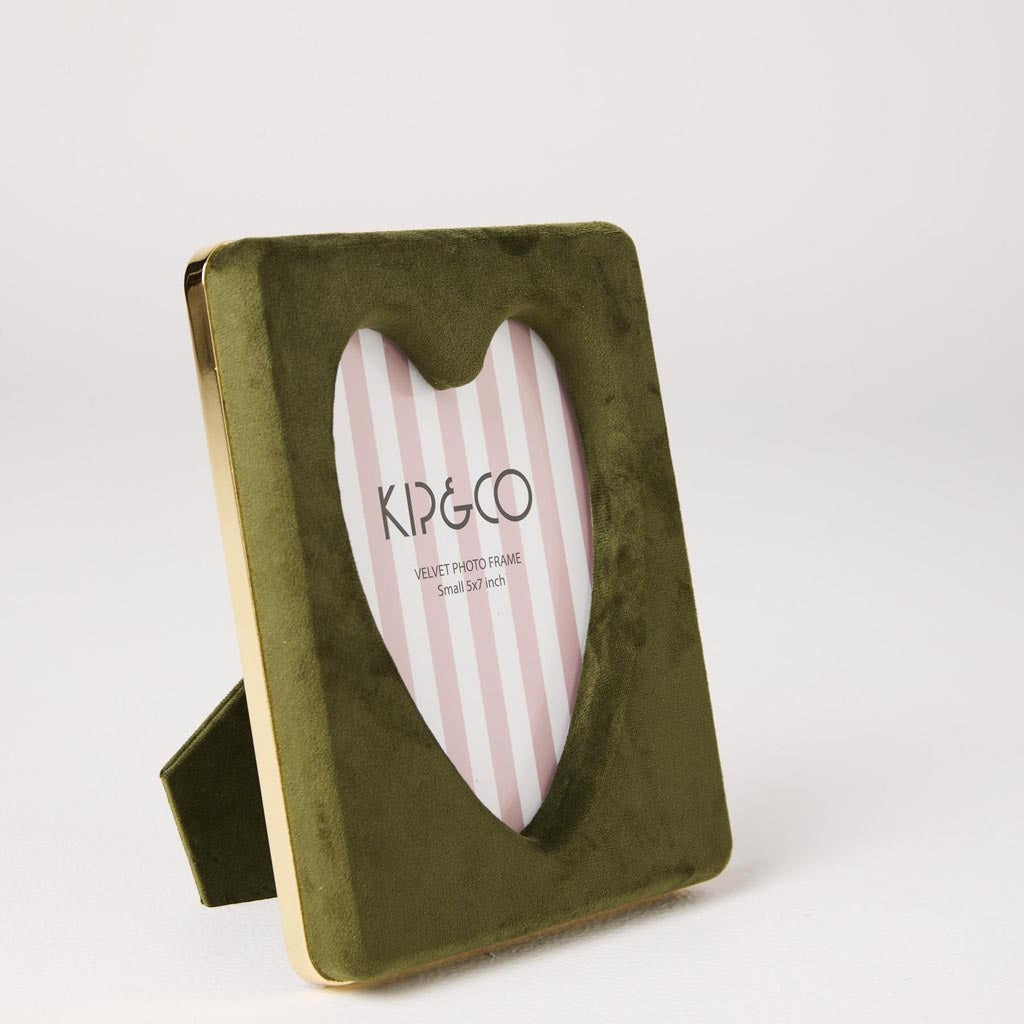 The image is of a decorative photo frame made from velvet material. The frame is designed in a heart shape and features a vibrant, multicolored pattern that resembles a campsite theme. The colors are rich and varied, giving the frame a lively and eye-catching appearance. The frame is intended to hold a photo measuring 6 x 8.5 inches.