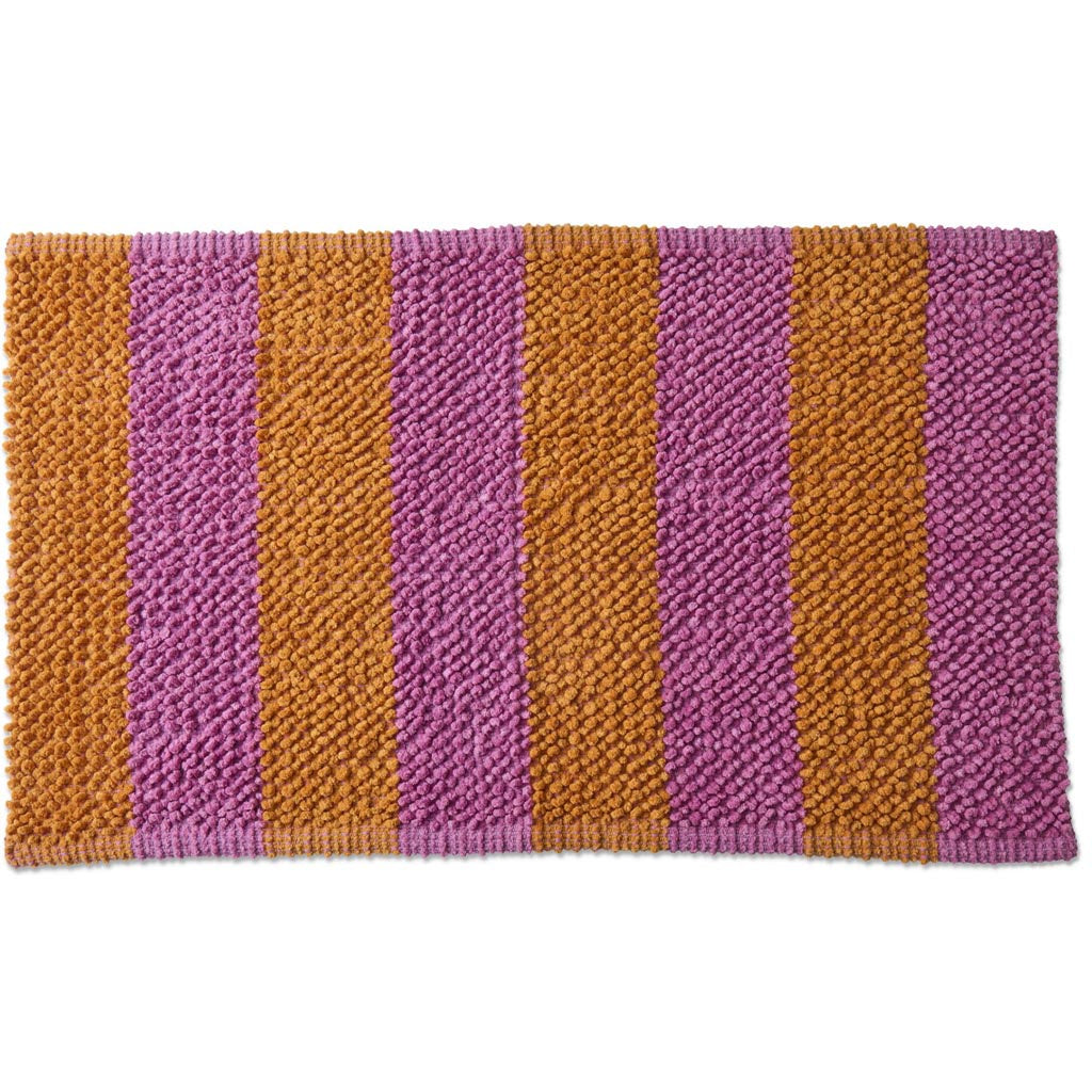 The image is of a colorful bath mat with a striped pattern. The stripes are arranged in a variety of vibrant colors, including shades of pink, orange, yellow, green, blue, and purple. The mat appears to be made of a soft, plush material, likely designed to be both comfortable and absorbent. The overall design is playful and eye-catching, adding a fun and lively touch to a bathroom setting.
