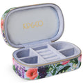 The image shows a small, rectangular velvet jewelry box in a soft pastel pink color. The box has a smooth, plush texture typical of velvet material. It features a gold-colored zipper that runs along the edge, providing a secure closure. The zipper pull is also gold and has a small, elegant design. The box is likely designed for travel, as it is compact and portable, making it convenient for storing and protecting jewelry items while on the go. The background is a simple, neutral color, allowing the jewelry 