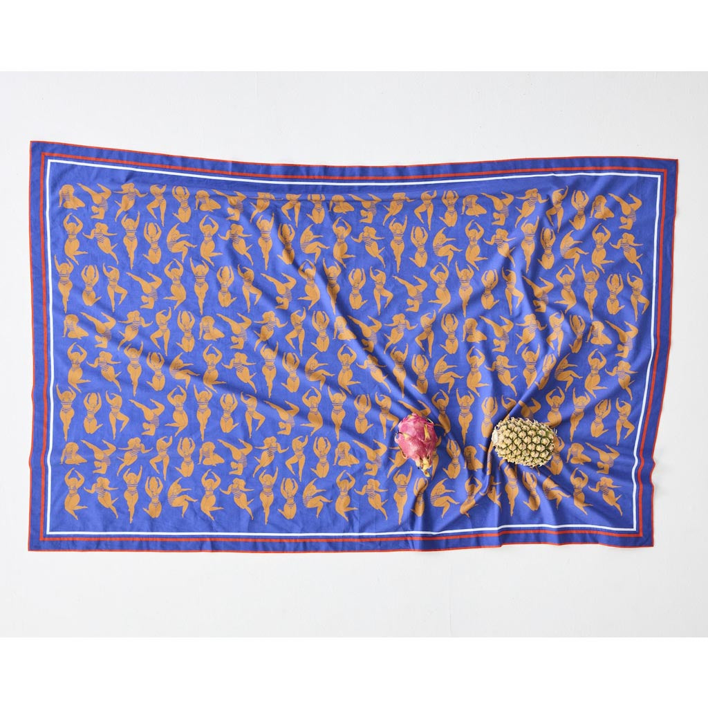 The image is of a colorful sarong made from organic cotton. The sarong features a vibrant design with a mix of warm colors, including shades of orange, pink, and yellow, reminiscent of a sun-kissed theme. The fabric appears lightweight and soft, suitable for beachwear or as a stylish wrap. The sarong is displayed against a plain background, highlighting its intricate patterns and vivid hues.