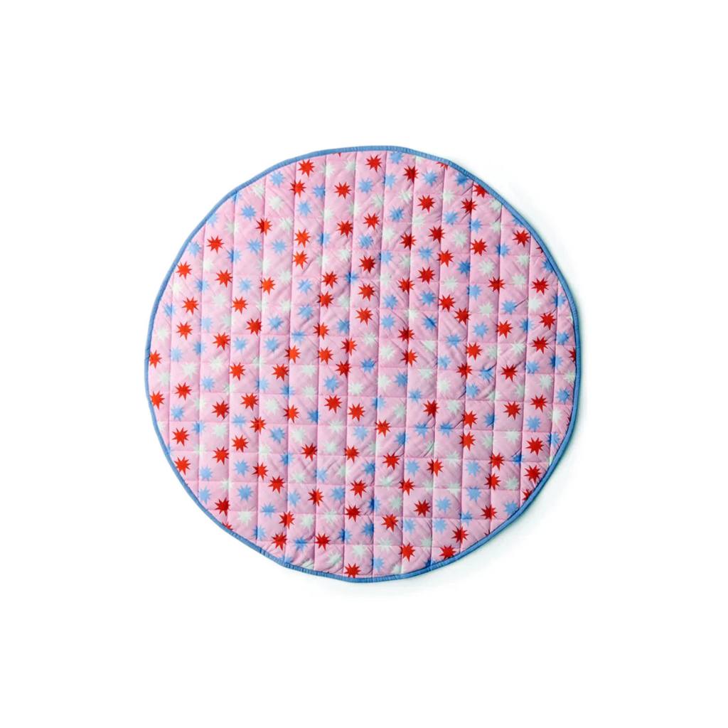 Round quilted mat with red and blue star pattern on a pink background
