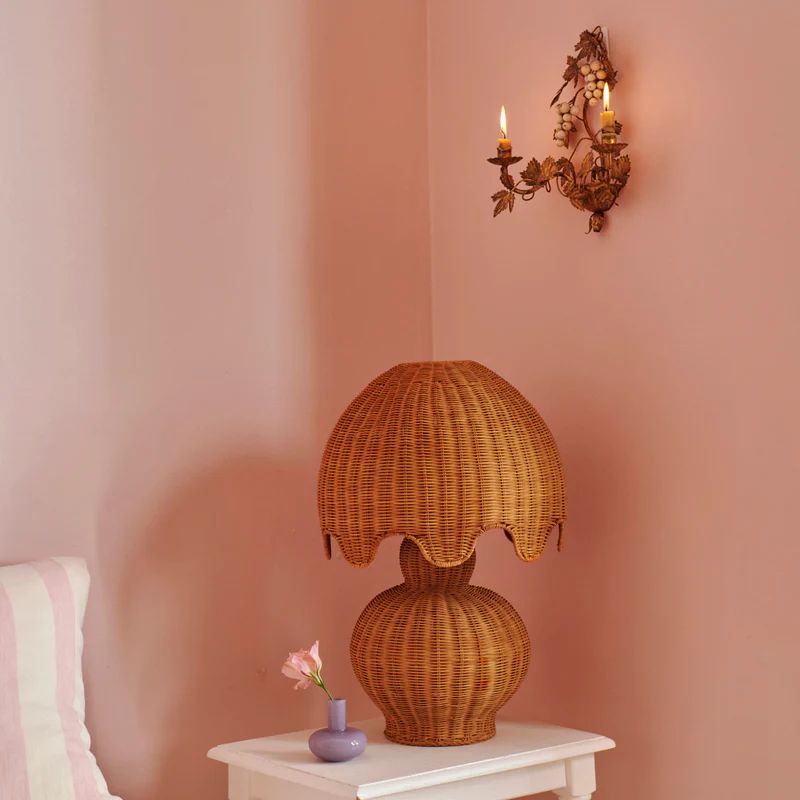 The image shows a beautifully designed Genie Rattan Lamp by Kip & Co. The lamp features a handwoven rattan shade that exudes a warm, cozy glow, perfect for brightening up any space. Its natural texture and intricate weaving highlight the craftsmanship and ethical production behind the piece, making it both a stylish and responsible choice for home decor.