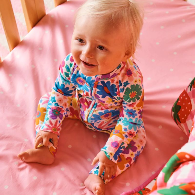 The image likely showcases Kip &amp; Co&#39;s Rainbow Flowers Romper, a vibrant and colorful piece of clothing designed for comfort and style. The romper features a playful floral pattern with a rainbow of colors, perfect for adding a pop of color to any wardrobe. It is available at Cove Beach Essentials and is noted for being eco-friendly, aligning with sustainable fashion practices.