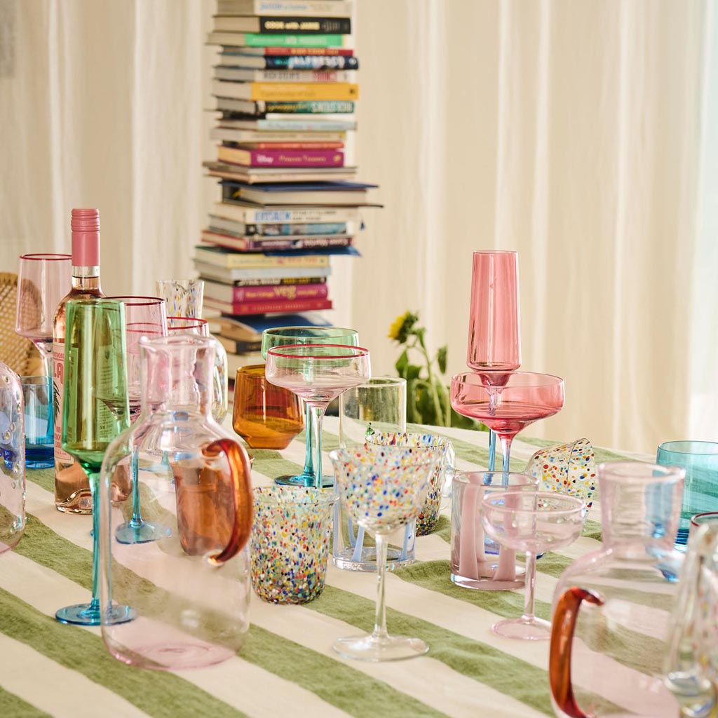 The image shows a set of two champagne glasses from Kip & Co. Each glass features a unique and artistic design with a blue robin motif. The glasses are elegantly shaped with a slender stem and a wide, shallow bowl, typical of traditional champagne coupes. The blue robin design is intricately detailed, adding a touch of whimsy and color to the otherwise clear glass. The glasses are positioned side by side against a plain background, highlighting their artistic design and craftsmanship.