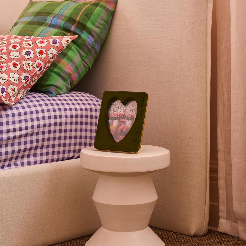 The image is of a photo frame designed by Kip & Co, known as the Campsite Heart Velvet Photo Frame. The frame is sized to hold a 6 x 8 inch photo. It features a plush, velvet texture with a vibrant and colorful heart pattern, giving it a cozy and stylish appearance. The frame's design is likely intended to add a touch of warmth and personality to any space where it is displayed.