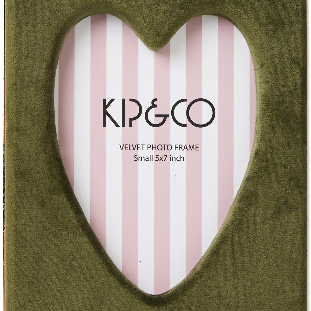 The image is of a photo frame designed by Kip & Co, known as the Campsite Heart Velvet Photo Frame. The frame is sized to hold a 6 x 8 inch photo. It features a plush, velvet texture with a vibrant and colorful heart pattern, giving it a cozy and stylish appearance. The frame's design is likely intended to add a touch of warmth and personality to any space where it is displayed.