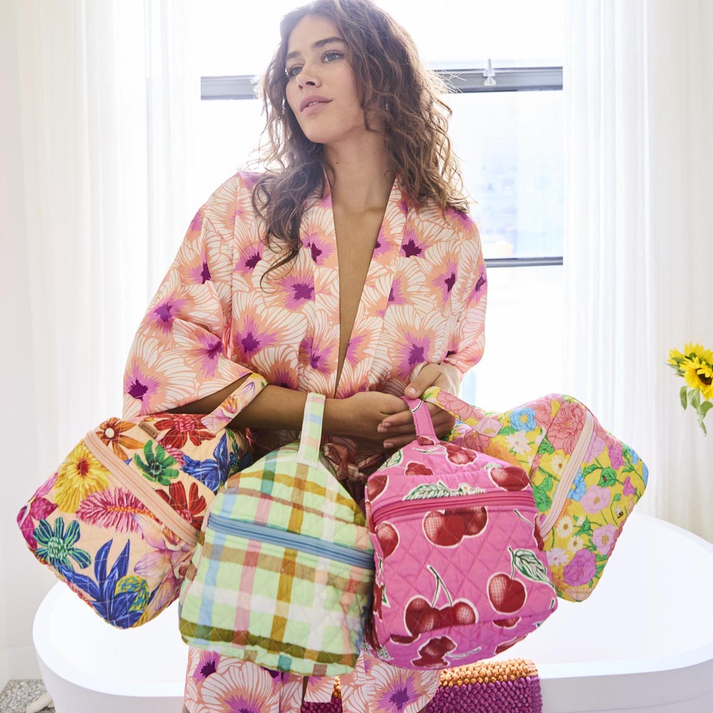 The image shows a quilted cotton toiletry case with a colorful checkered pattern. The design features a mix of pastel colors, including shades of pink, mint green, and yellow, arranged in a candy check pattern. The case has a rectangular shape with a zipper closure on the top, and it appears to be padded for added protection of its contents. The overall look is vibrant and playful, suitable for storing toiletries or small personal items.