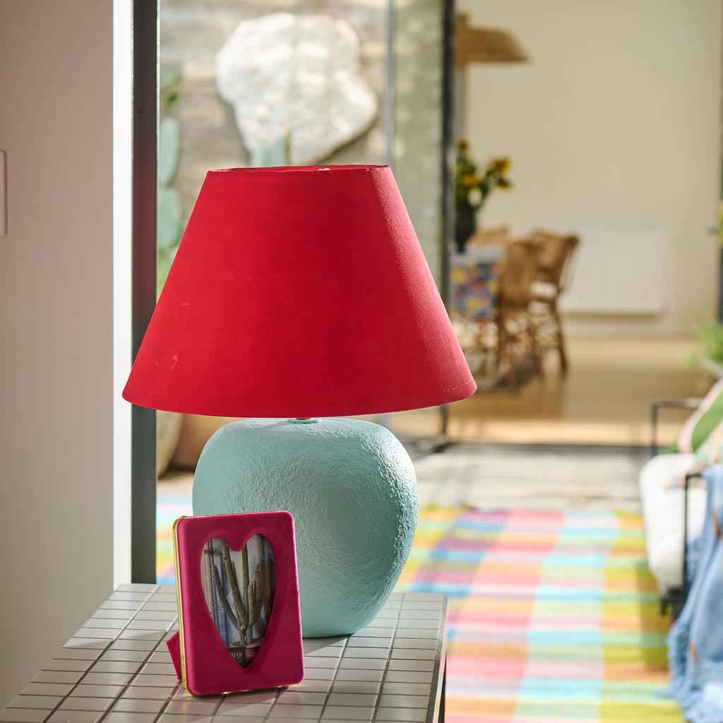 The image is of a photo frame designed by Kip & Co. It features a heart-shaped design and is made from a soft, plush velvet material in a desert pink color. The frame is intended to hold a 6 x 8-inch photograph. The velvet texture gives it a luxurious and cozy appearance, making it a stylish and decorative piece for displaying cherished memories.