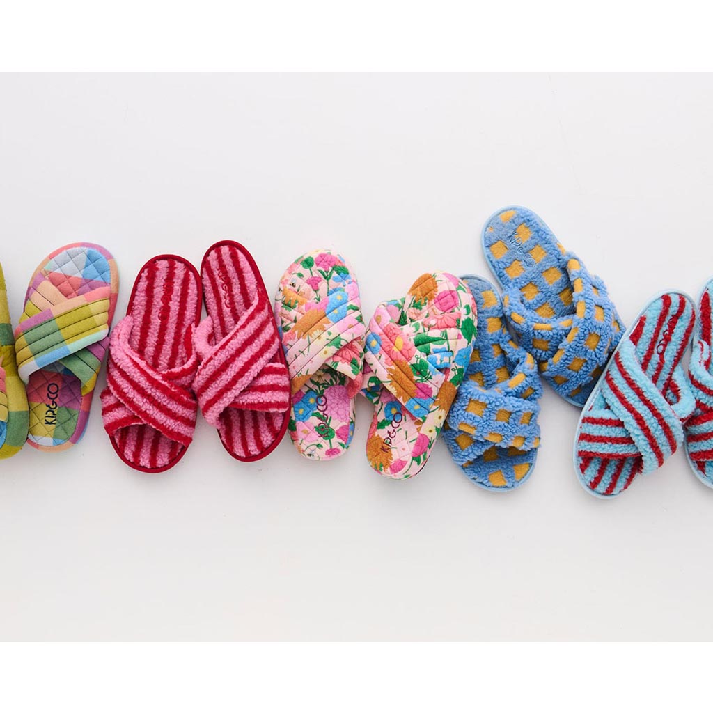 The image shows a pair of adult slippers made from quilted velvet material. The slippers are designed with a plush, luxurious texture and have a vibrant, colorful pattern that resembles a sun motif. The interior of the slippers appears to be lined with a soft, cozy fabric, providing comfort and warmth. The slippers have a rounded toe and a slip-on style, making them easy to wear. They are displayed against a plain background, highlighting their design and texture.