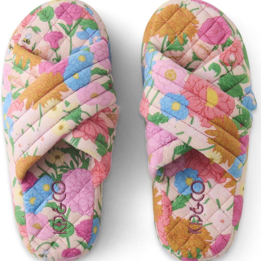 The image shows a pair of adult slippers made from quilted velvet material. The slippers are designed with a cozy and plush appearance, featuring a soft, padded texture that suggests comfort and warmth. The color of the slippers is a rich, warm shade, possibly a deep mustard or golden hue, which adds to their luxurious look. The slippers have a simple, slip-on design with a rounded toe and a slightly raised back for added support. They are displayed against a plain background, highlighting their texture and