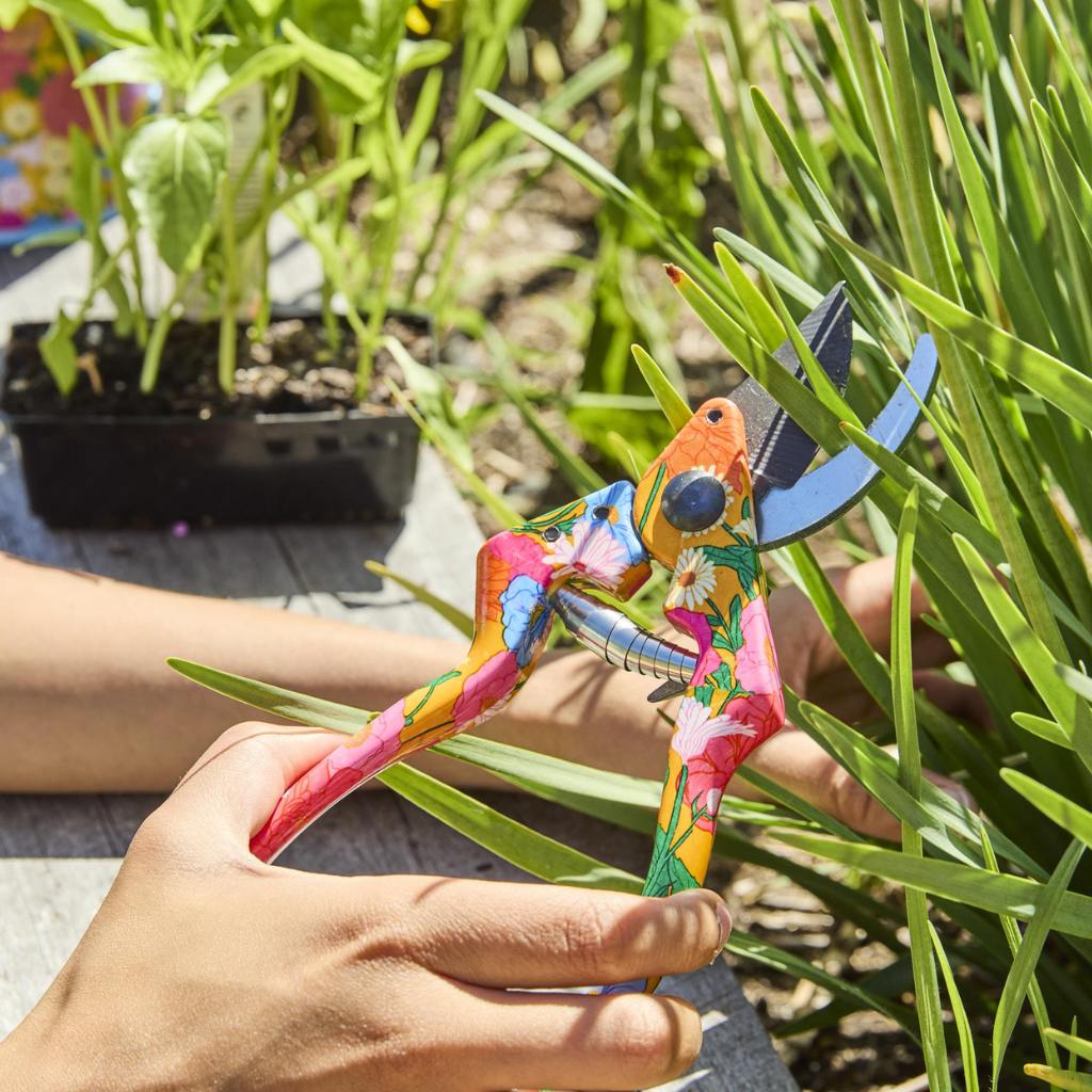 The image shows a gardening set consisting of a pair of yellow garden secateurs and a pair of gloves. The secateurs have a sleek design with a bright yellow handle, which stands out against the background. The gloves are designed for gardening, featuring a colorful pattern that includes shades of yellow, green, and other complementary colors. The set is likely displayed on a neutral background to highlight the vibrant colors of the tools.