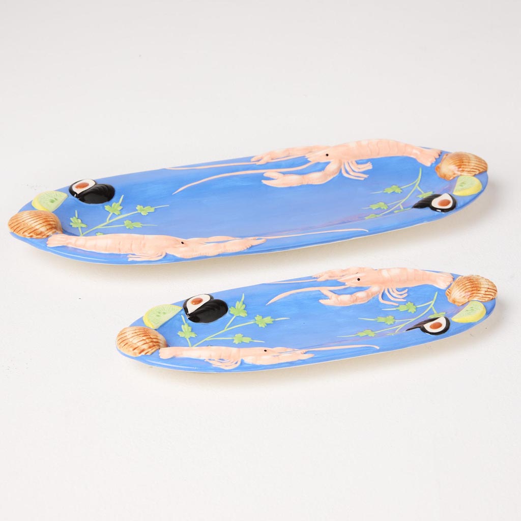 The image is of an oval-shaped platter with a vibrant and colorful design. The platter features an artistic depiction of various sea creatures and marine elements, such as fish, shells, and seaweed, all intricately arranged. The colors are bold and eye-catching, with a mix of blues, greens, and other bright hues, giving the platter a lively and whimsical appearance. The platter is likely made of ceramic or a similar material, and its design suggests it is intended for decorative use or serving seafood dishe