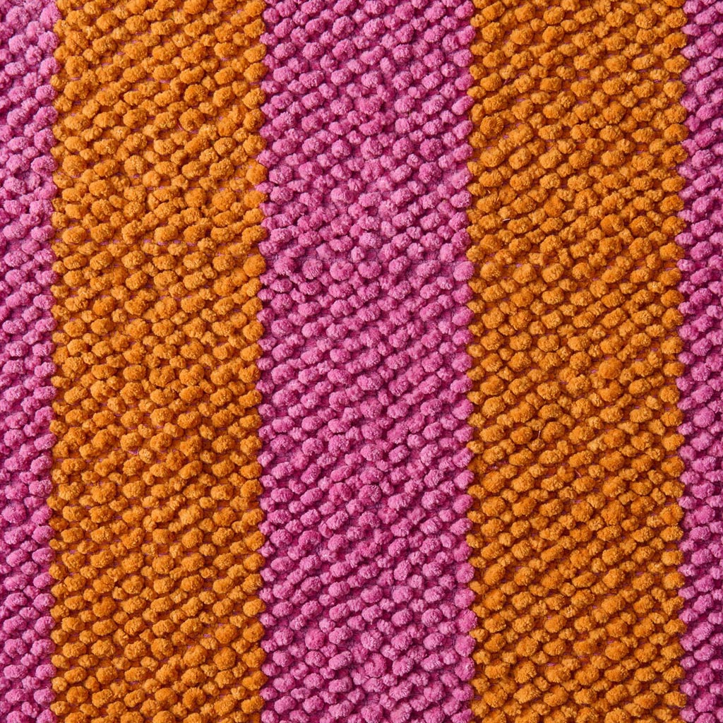 The image is of a colorful bath mat with a striped pattern. The stripes are arranged in a variety of vibrant colors, including shades of pink, orange, yellow, green, blue, and purple. The mat appears to be made of a soft, plush material, likely designed to be absorbent and comfortable underfoot. The edges of the mat are neatly finished, and the overall design is playful and eye-catching, suitable for adding a pop of color to a bathroom setting.