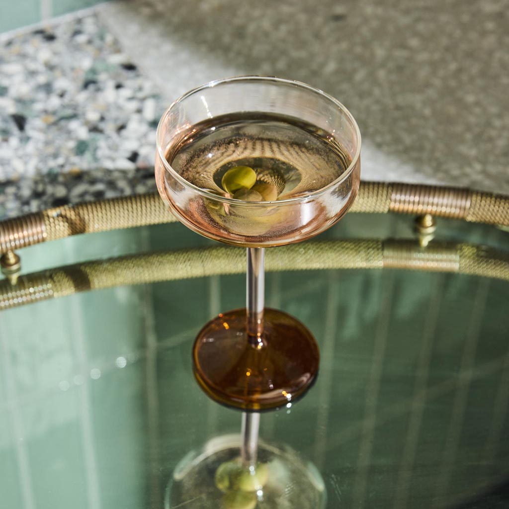 The image shows a set of two margarita glasses from Kip & Co. Each glass has a unique and colorful design, featuring a combination of pastel and vibrant hues reminiscent of marshmallows and marmalade. The glasses have a classic margarita shape with a wide, shallow bowl and a short stem. They are displayed against a plain background, highlighting their artistic and playful appearance.