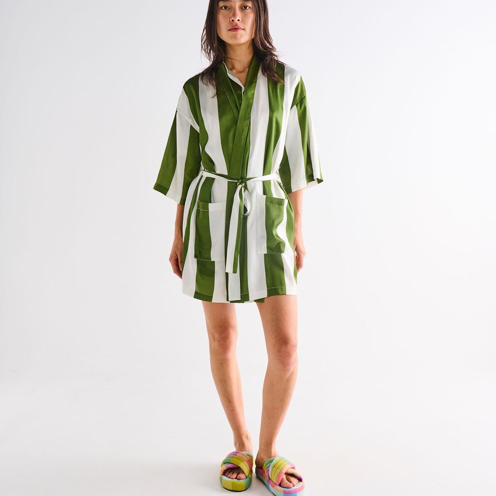 The image is of a robe made from eco-friendly satin material. The robe features a design with horizontal stripes in various shades of green, resembling moss. It has a relaxed fit with a belt around the waist for closure. The fabric appears smooth and shiny, typical of satin, giving it a luxurious look. The robe is displayed on a plain background, highlighting its texture and color pattern.