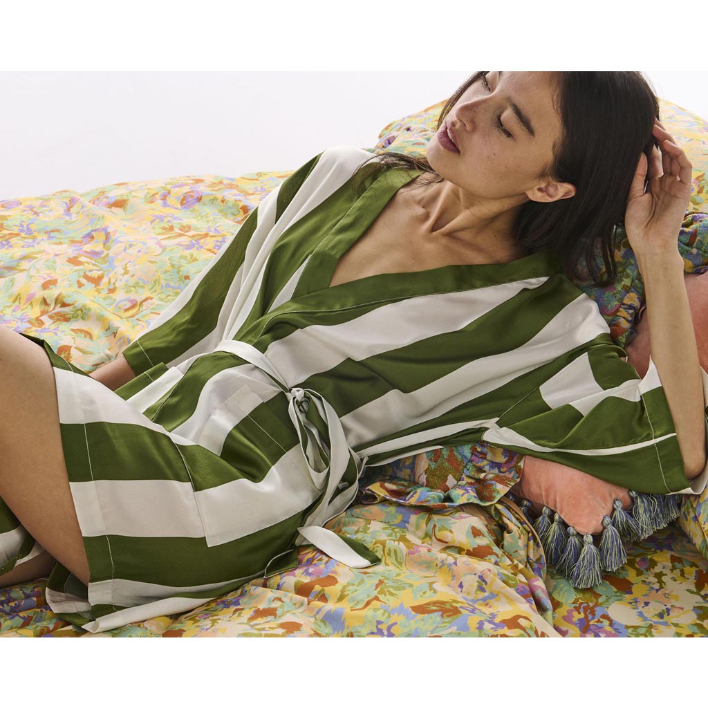 The image is of a robe made from eco-friendly satin material. The robe features a design with horizontal stripes in various shades of green, resembling moss. It has a relaxed fit with a belt at the waist for closure. The fabric appears smooth and shiny, typical of satin, giving it a luxurious look. The robe is displayed against a plain background, highlighting its texture and color pattern.