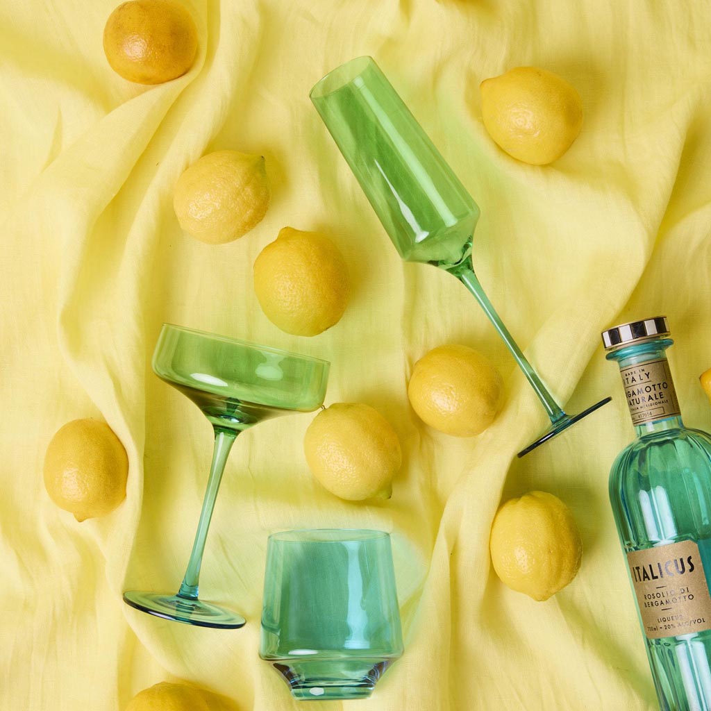 The image shows a set of two margarita glasses from Kip & Co, named "Pistachio Crush." The glasses have a unique and stylish design, featuring a textured surface with a greenish hue reminiscent of pistachios. The stems of the glasses are elegantly shaped, adding a touch of sophistication to the overall appearance. The glasses are displayed against a plain background, highlighting their intricate details and vibrant color.