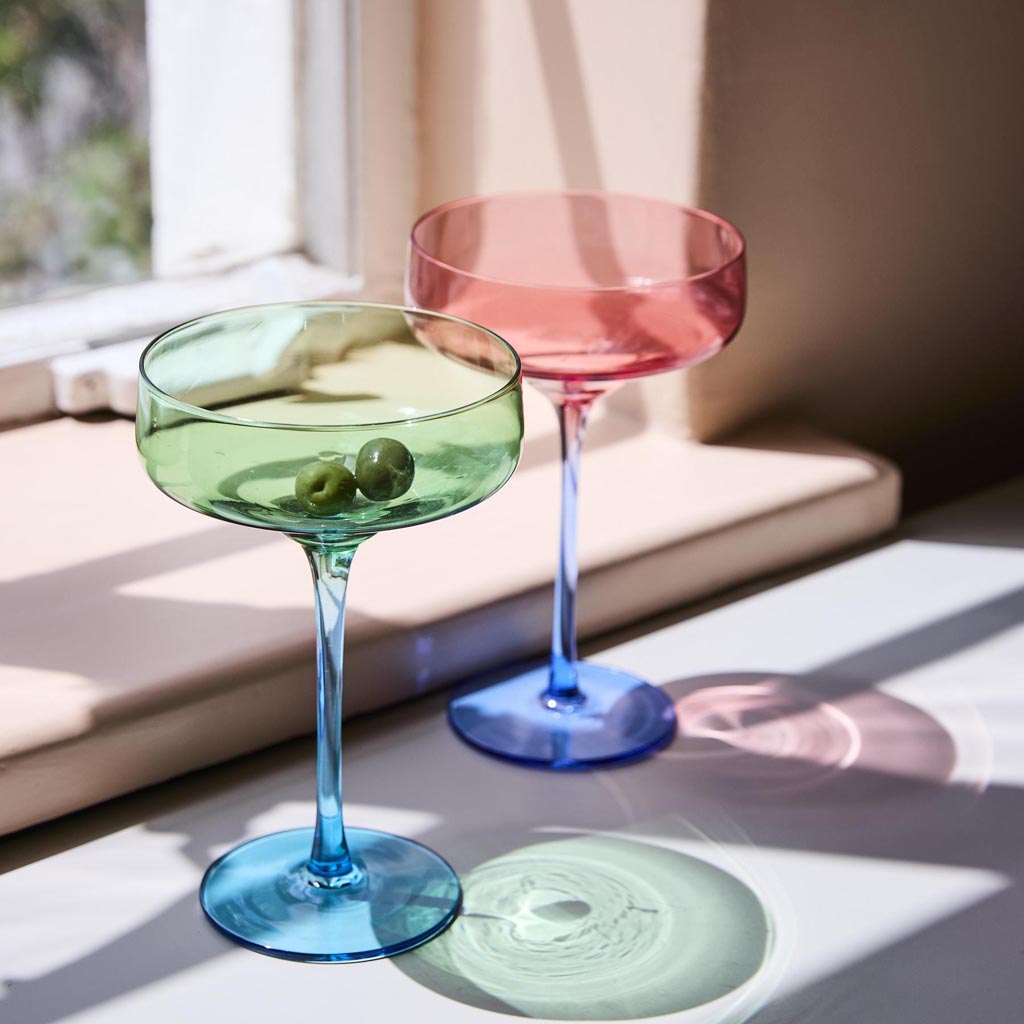 The image shows a set of two margarita glasses from Kip & Co, named "Pistachio Crush." The glasses have a unique and stylish design, featuring a textured surface with a pistachio green hue. The stems of the glasses are elegantly shaped, adding a touch of sophistication. The overall appearance is vibrant and eye-catching, making them perfect for serving margaritas or other cocktails in a fashionable manner.