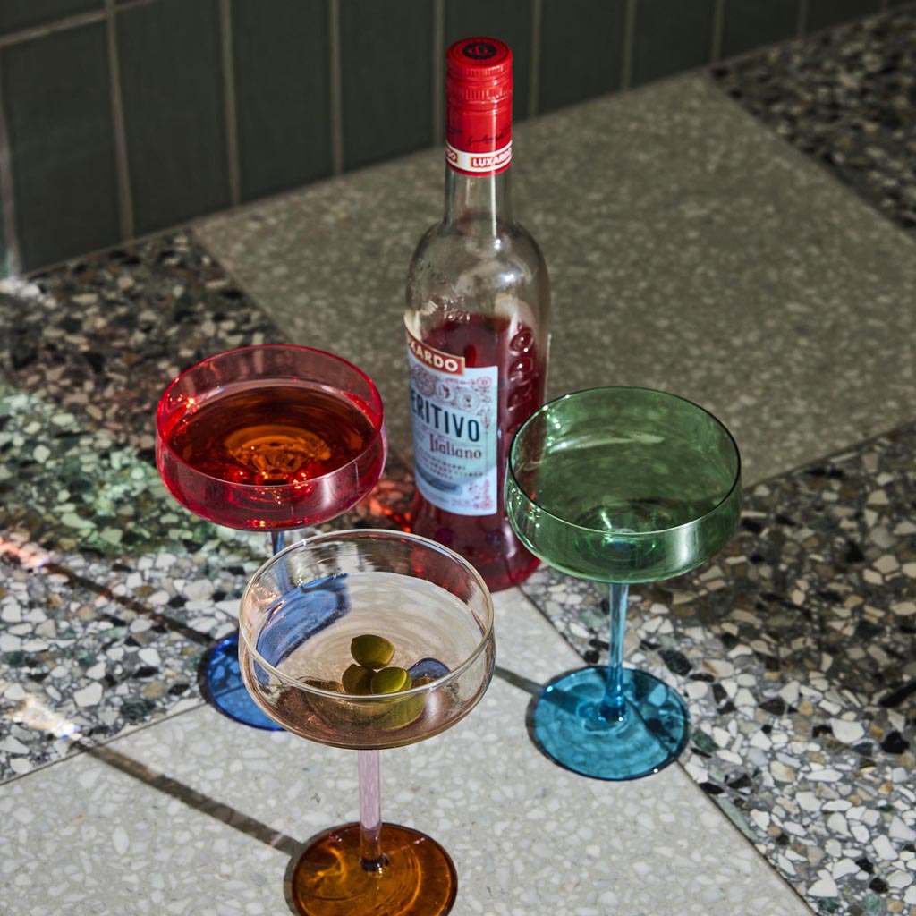 The image shows a set of two margarita glasses from Kip & Co, named "Pistachio Crush." The glasses have a unique and stylish design, featuring a textured surface with a greenish hue reminiscent of pistachio. The stems of the glasses are elegantly shaped, adding a touch of sophistication to the overall appearance. The glasses are displayed against a plain background, highlighting their intricate details and vibrant color.