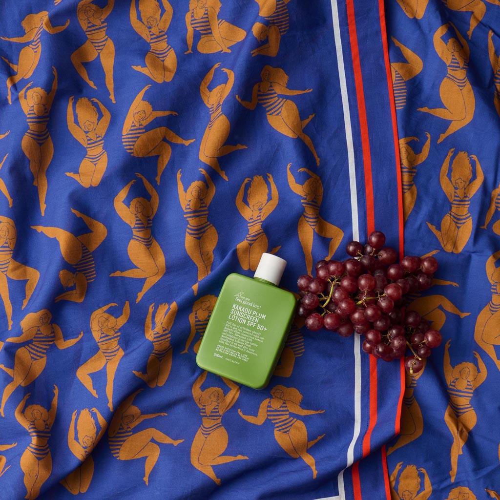 The image is of a colorful sarong made from organic cotton. The sarong features a vibrant design with a mix of warm colors, including shades of orange, pink, and yellow, reminiscent of a sun-kissed theme. The fabric appears lightweight and soft, suitable for use as a beach cover-up or a stylish wrap. The sarong is displayed in a way that highlights its pattern and texture, giving a sense of its size and versatility.