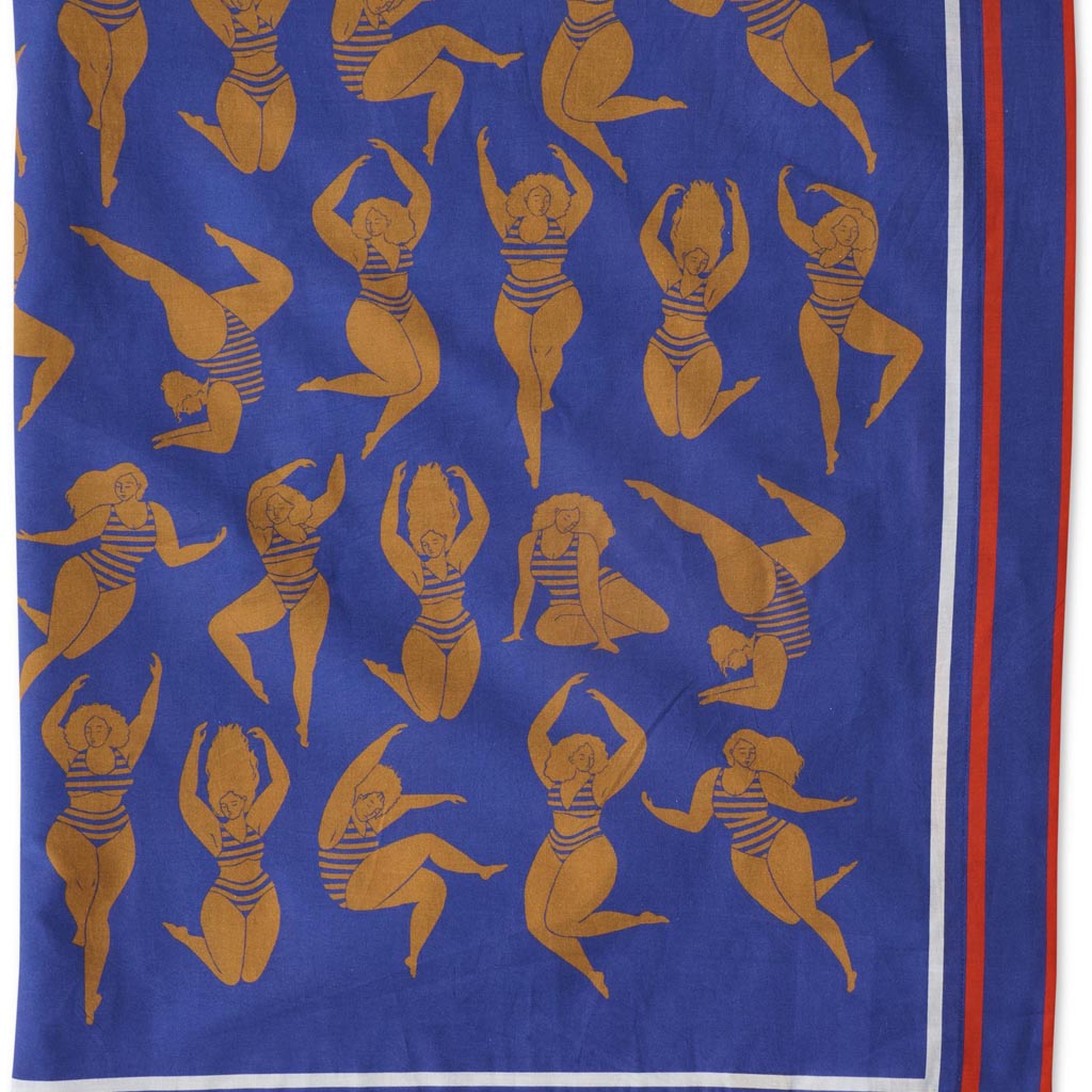 The image is of a colorful sarong made from organic cotton. The sarong features a vibrant design with a mix of warm colors, including shades of orange, pink, and yellow, reminiscent of a sun-kissed theme. The fabric appears lightweight and soft, suitable for beachwear or as a stylish wrap. The sarong is displayed against a plain background, highlighting its intricate patterns and vivid hues.