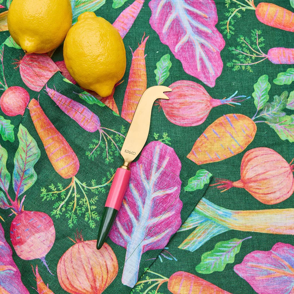 The image shows a cheese knife from the Kip & Co Tuscan Days Brasserie collection. The knife features a sleek and elegant design with a polished metal blade and a handle that appears to be made of a smooth, colorful material, possibly resin or acrylic, with a marbled pattern. The handle's colors are reminiscent of a Tuscan landscape, with warm earthy tones and hints of green and blue. The knife is designed for cutting and serving cheese, combining functionality with a stylish aesthetic.