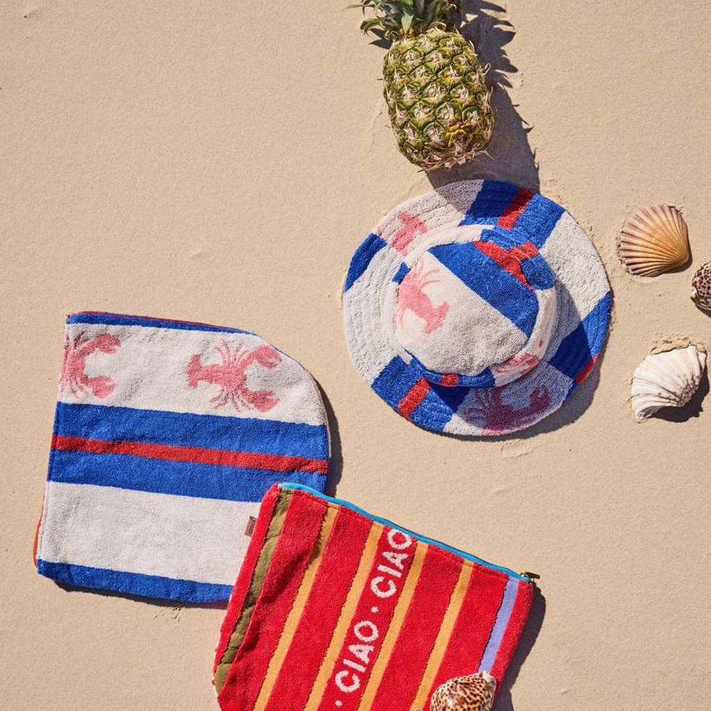 Lobster Fan Club hat and pouches laid out on the sand