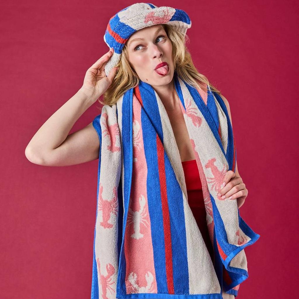 Woman with the Lobster Fan Club towel and hat on a red background