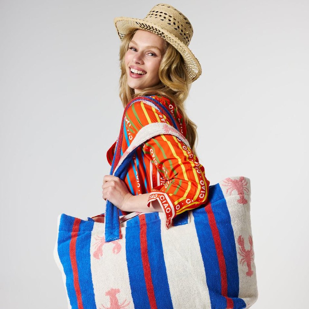Woman in a straw hat carrying the Lobster Fan Club beach bag