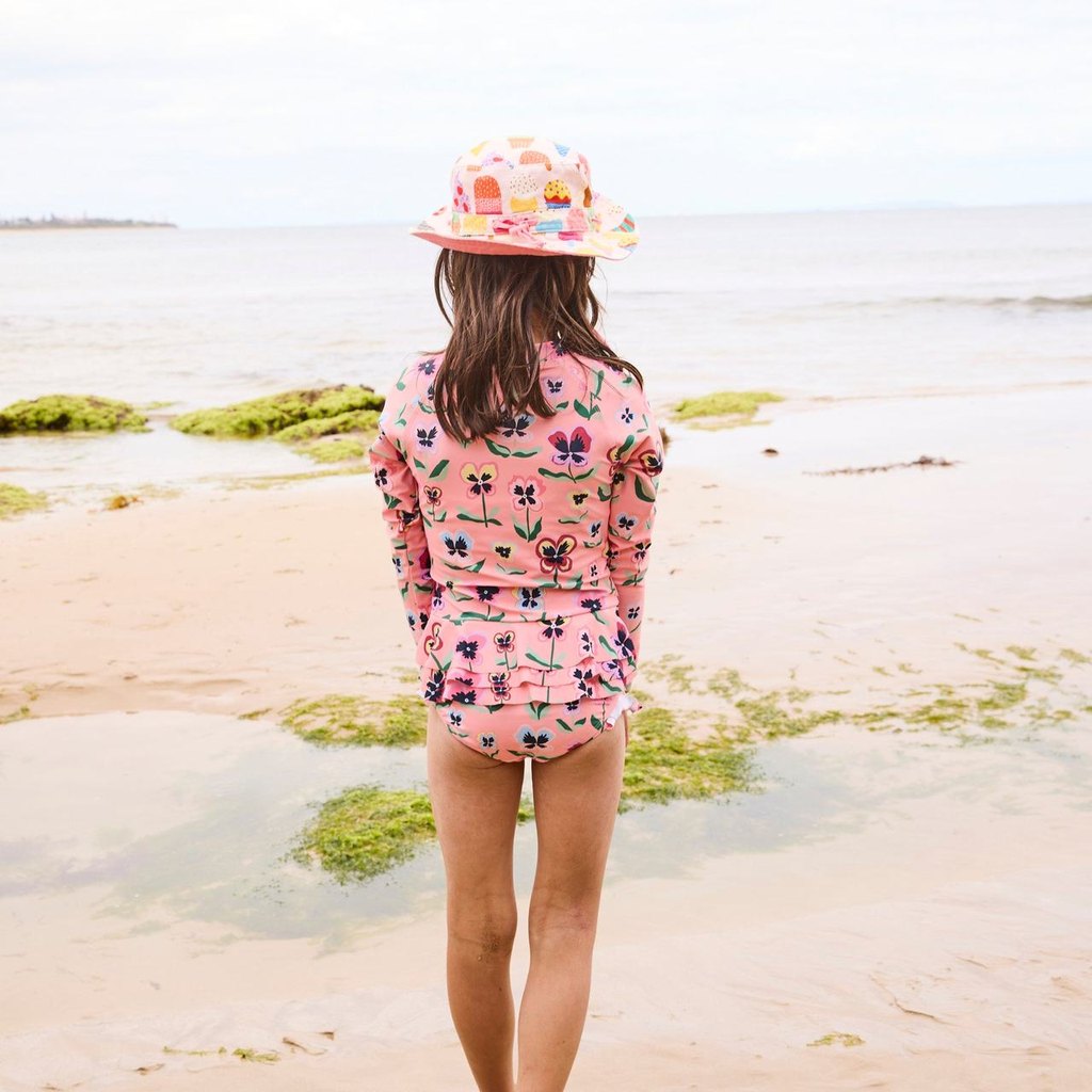 Girl walking on the beach in Pretty Pansy bathers, back view