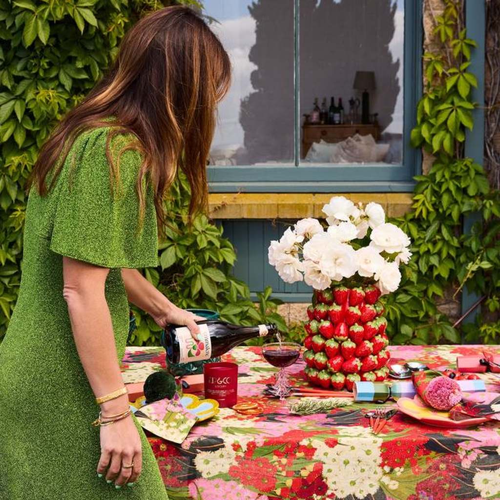 Woman pouring drinks beside the Strawberry Jam vase at a garden lunch