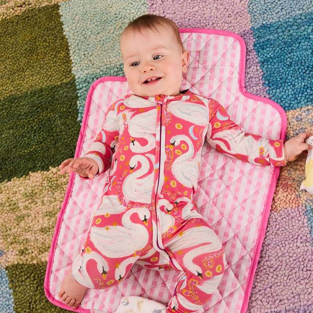 Baby lying on the Swanette change mat on a checked rug