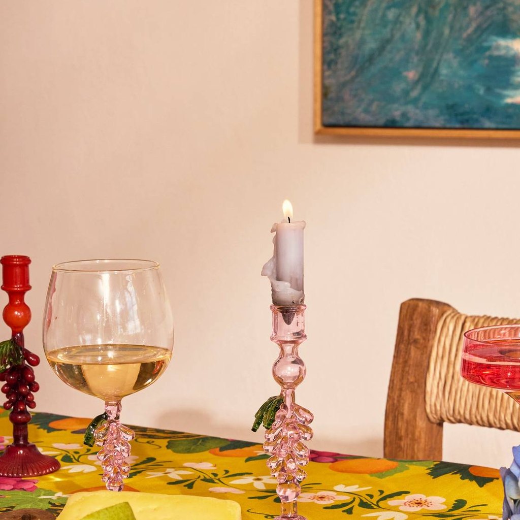 Lit pink Under The Vine candlestick on a floral dining table