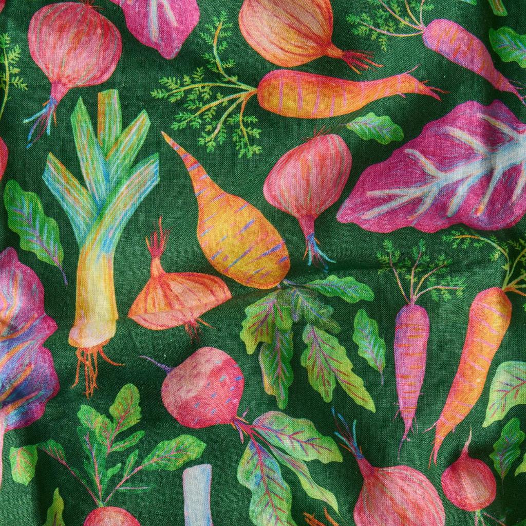 The image is of a tea towel featuring a colorful and artistic design of a veggie soup recipe. The towel displays various illustrated vegetables such as carrots, tomatoes, and onions, along with herbs and spices, all arranged around the text of the recipe. The recipe text is likely printed in a clear, easy-to-read font, providing step-by-step instructions for making the soup. The overall design is vibrant and visually appealing, making it both a functional kitchen item and a decorative piece.