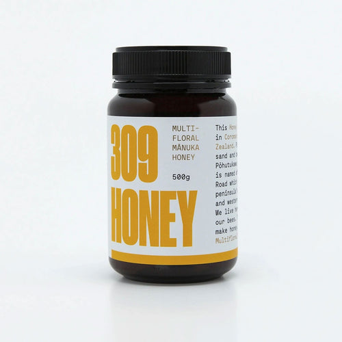 A jar of multifloral honey with a yellow label, featuring the text "100% Multifloral Honey" and "MGO 100+" prominently displayed. The jar is 500g in size and is part of a product line, as indicated by the branding and design elements on the label. The background is plain, emphasizing the product.