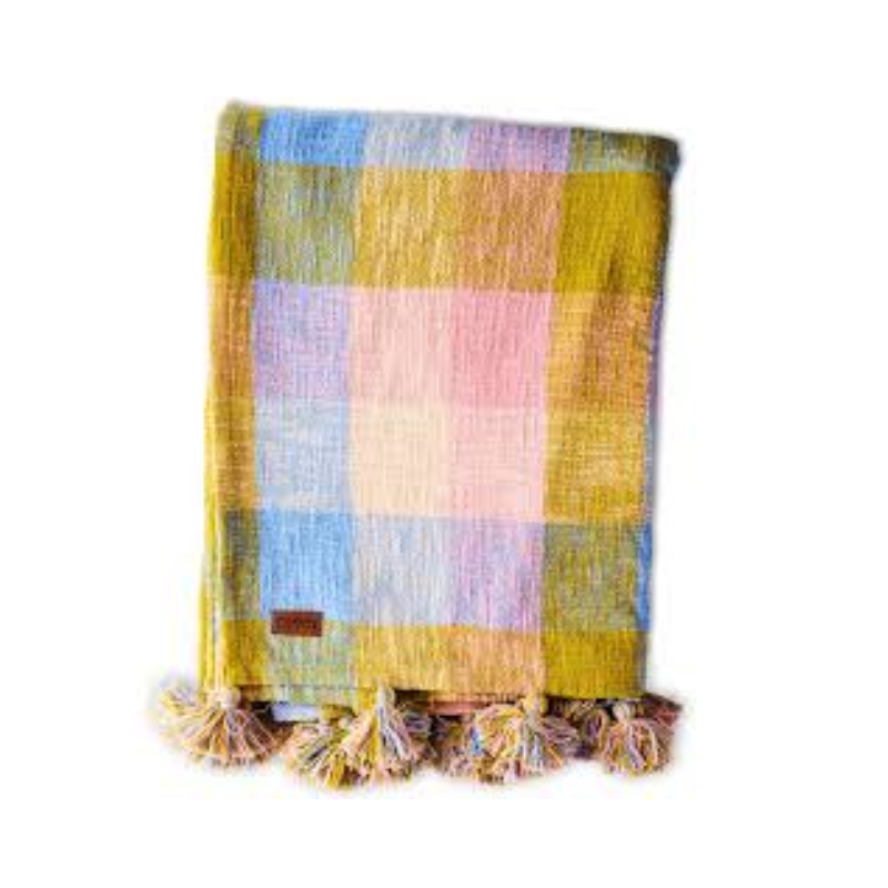 The image likely features Kip & Co's Corfu Tartan Throw, showcasing its vibrant colors and intricate tartan pattern. The throw is made from 100% cotton, adding a cozy and stylish touch to any space.